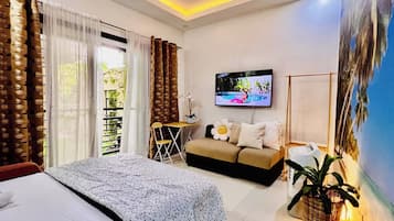 Una habitación de hotel moderna con una cama, un sofá, un televisor y un ventanal con cortinas.