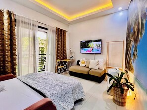 Ein modernes Hotelzimmer mit Bett, Sofa, Fernseher und einem großen Fenster mit Vorhängen.