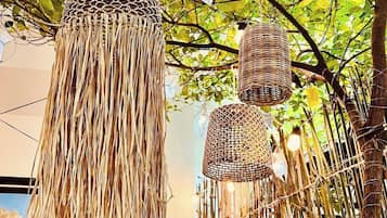 Ein dekoratives Objekt aus Naturmaterialien, möglicherweise ein gewebter Korb oder ein Kunstwerk, das an einem Baum hängt.
