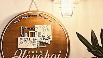 Eine an der Wand befestigte Schild mit einer gemütlichen Wohnbild-Illustration und dem Text 'Your cozy home in the city' und 'Bali Hai'.