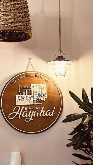 Eine an der Wand befestigte Schild mit einer gemütlichen Wohnbild-Illustration und dem Text 'Your cozy home in the city' und 'Bali Hai'.