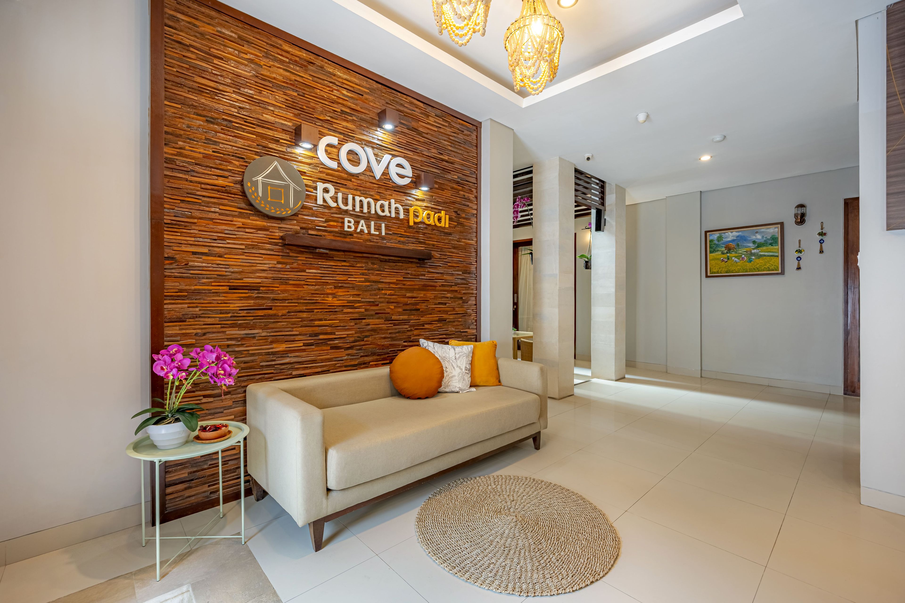 A modern interior with a wooden accent wall, a sofa, a small table with a plant, and a round rug.