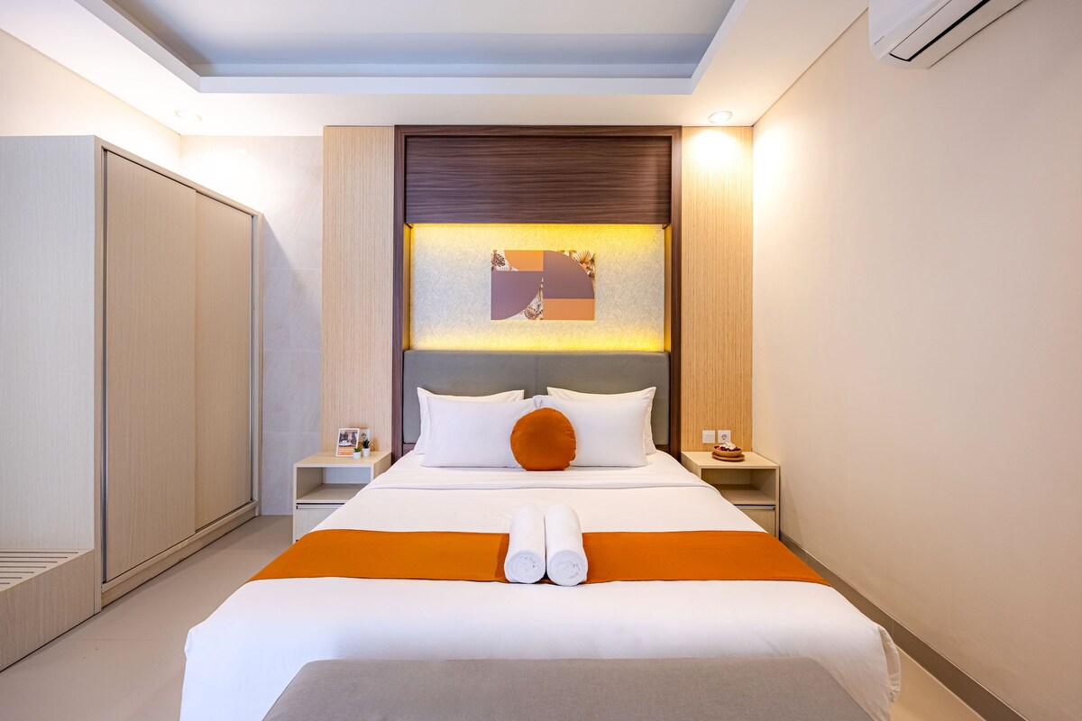 A hotel room with a bed, nightstands, a wall-mounted artwork, and a wardrobe.
