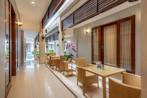 A corridor with a dining area featuring wicker furniture and potted plants. - Cove Rumah Padi (Kabupaten Badung)