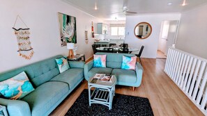 Una sala de estar con un sofá verde, una mesa de centro y una zona de comedor con una mesa y sillas.