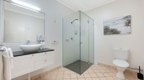A modern bathroom with a glass-enclosed shower, a white sink, and a toilet.
