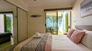 Un dormitorio con una cama, una mesita de noche, una ventana y vistas al exterior.