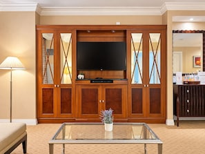 A hotel room with a large wooden entertainment unit, a flat-screen TV, a glass coffee table, and a bedside lamp. - MGM Signature 27F - F1 Track & Topgolf Views (Las Vegas)