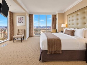 A hotel room with a large bed, a chair, a desk, and a view of the city. - MGM Signature 27F - F1 Track & Topgolf Views (Las Vegas)