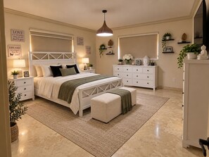 Quarto com cama, mesas de cabeceira, penteadeira e espelho.