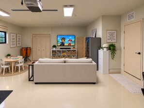 A living room with a sofa, television, and a play area with toys. - Redlands Retreat Pool + Volleyball Sleeps 10 (Miami)