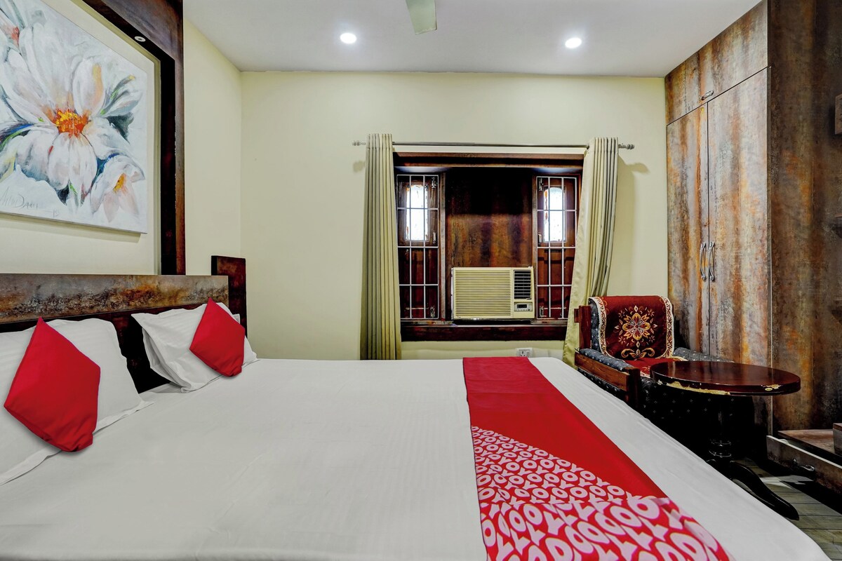 A hotel room with a bed, a chair, a table, and a large painting on the wall.