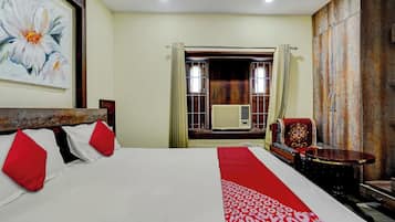 A hotel room with a bed, a chair, a table, and a large painting on the wall.