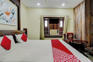 A hotel room with a bed, a chair, a table, and a large painting on the wall. - Super Hotel O Oxygen (Samudrapur)