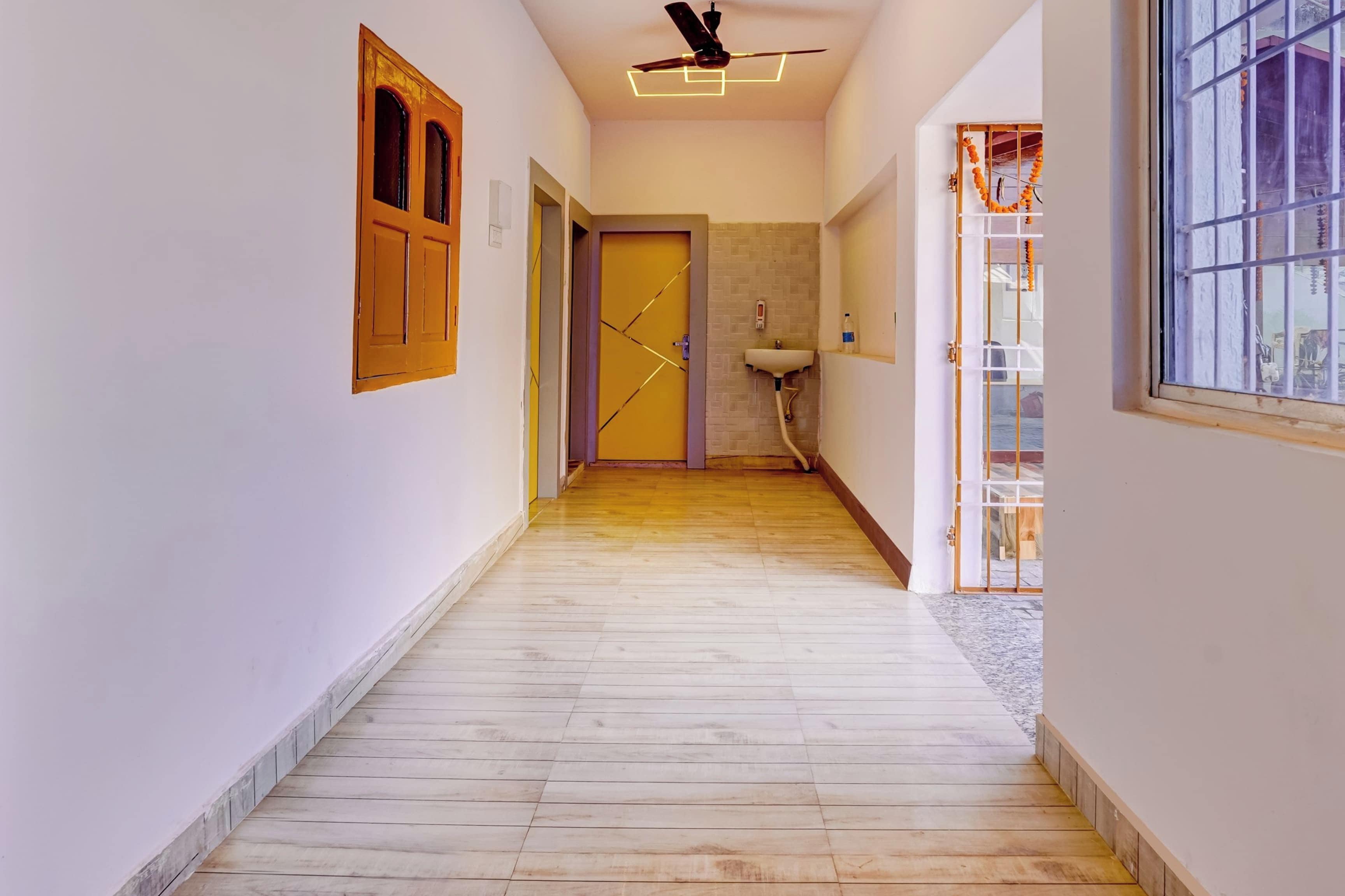 Un pasillo con piso de madera, ventilador de techo y una ventana con barrotes.