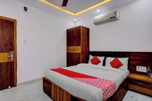 A bedroom with a bed, wooden wardrobe, and an air conditioning unit.