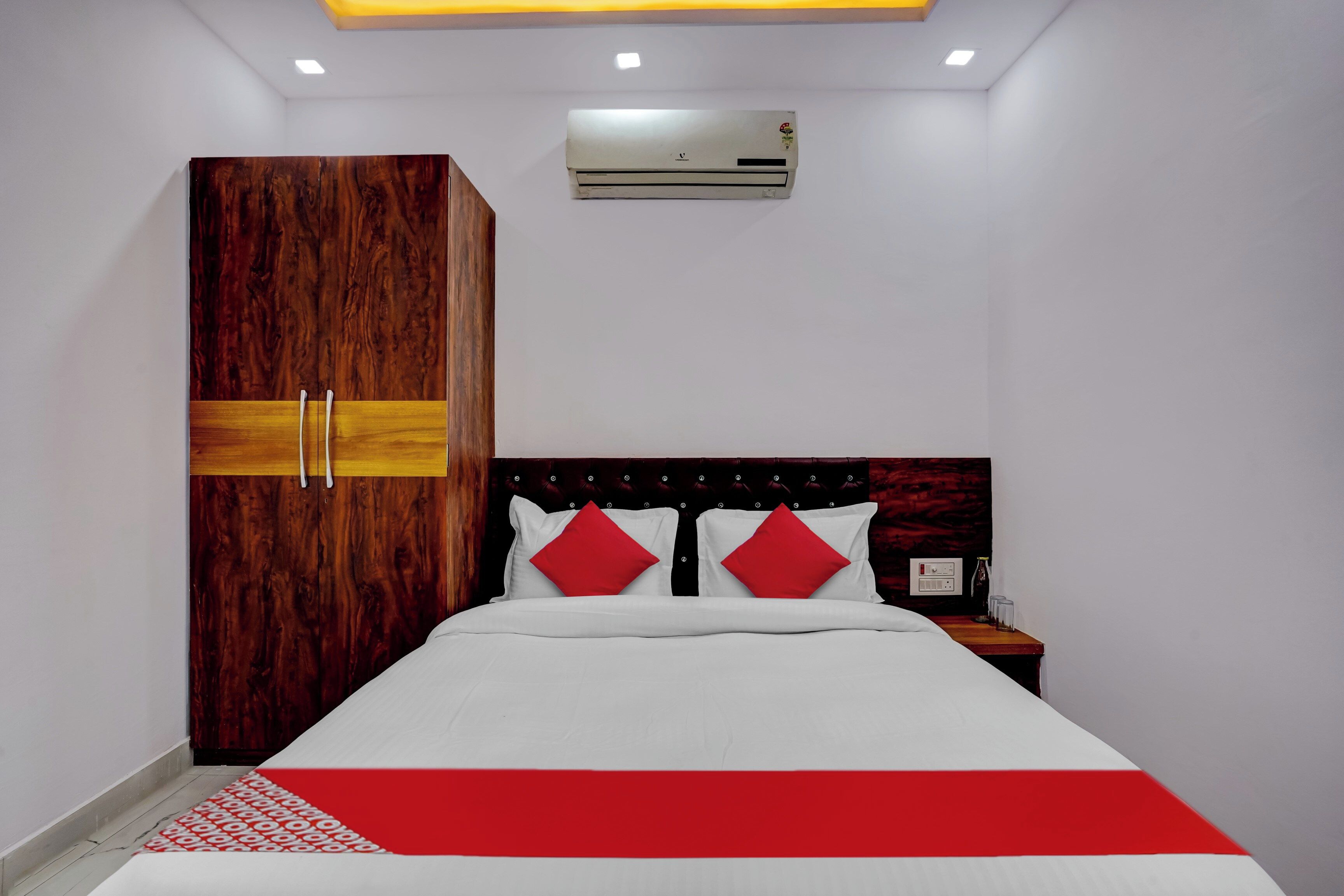 A bedroom with a bed, a wardrobe, a nightstand, and an air conditioning unit.