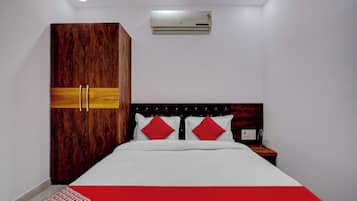 A bedroom with a bed, a wardrobe, a nightstand, and an air conditioning unit.
