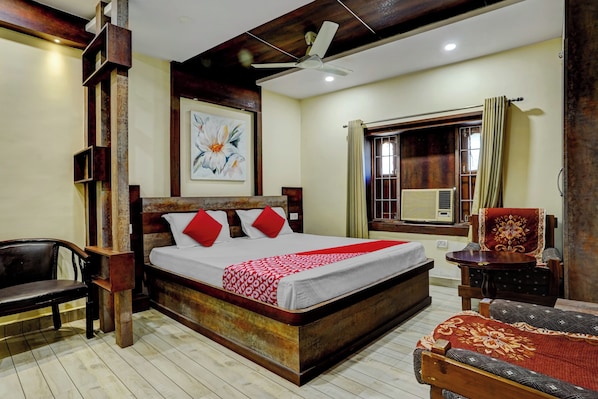 A hotel room with a large bed, a ceiling fan, a window with curtains, and a chair.