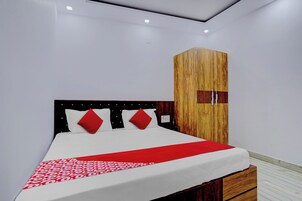 A modern bedroom with a bed, a wooden wardrobe, and a nightstand.