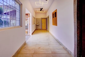 A hallway with a wooden floor, a ceiling fan, and a window on the left.