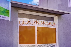 A building facade with a large, central door featuring a decorative metal grille and marigold garlands.