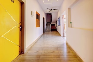 Un pasillo con piso de madera, un ventilador de techo y una escalera que sube a otro nivel.