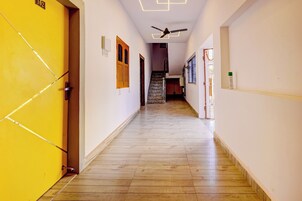Un pasillo con piso de madera, un ventilador de techo y una escalera que sube a otro nivel.