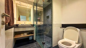 Een moderne badkamer met een douchecabine van glas, een wit toilet en een wastafel met spiegel.