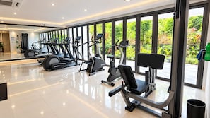 Een moderne sportschool met diverse fitnessapparaten, grote ramen en een schone, spiegelende vloer.
