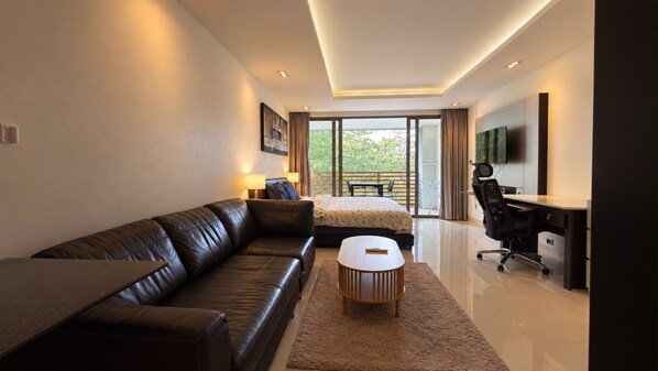 A modern bedroom with a leather sofa, a bed, a desk, and a large window.
