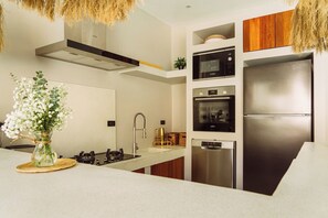 A modern kitchen with a stainless steel refrigerator, built-in oven, microwave, and gas stove. - Villa Malika – A Private Haven in the Tropics (Maret)