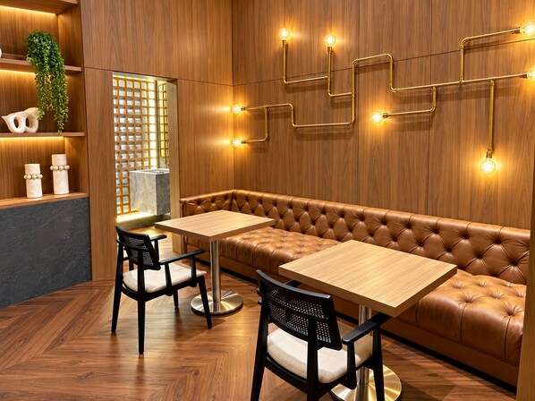 Een modern interieur met een houten wand, een leren bank, twee tafels en stoelen.
