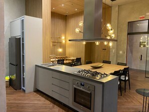 A modern kitchen with a central island, built-in appliances, and pendant lighting. - Cozy 1-bedroom apartment in soothing Itapema with AC (Itapema)