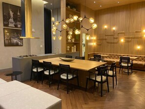 A modern dining area with a wooden table and chairs, a built-in kitchen island, and a seating area with a cushioned bench. - Cozy 1-bedroom apartment in soothing Itapema with AC (Itapema)