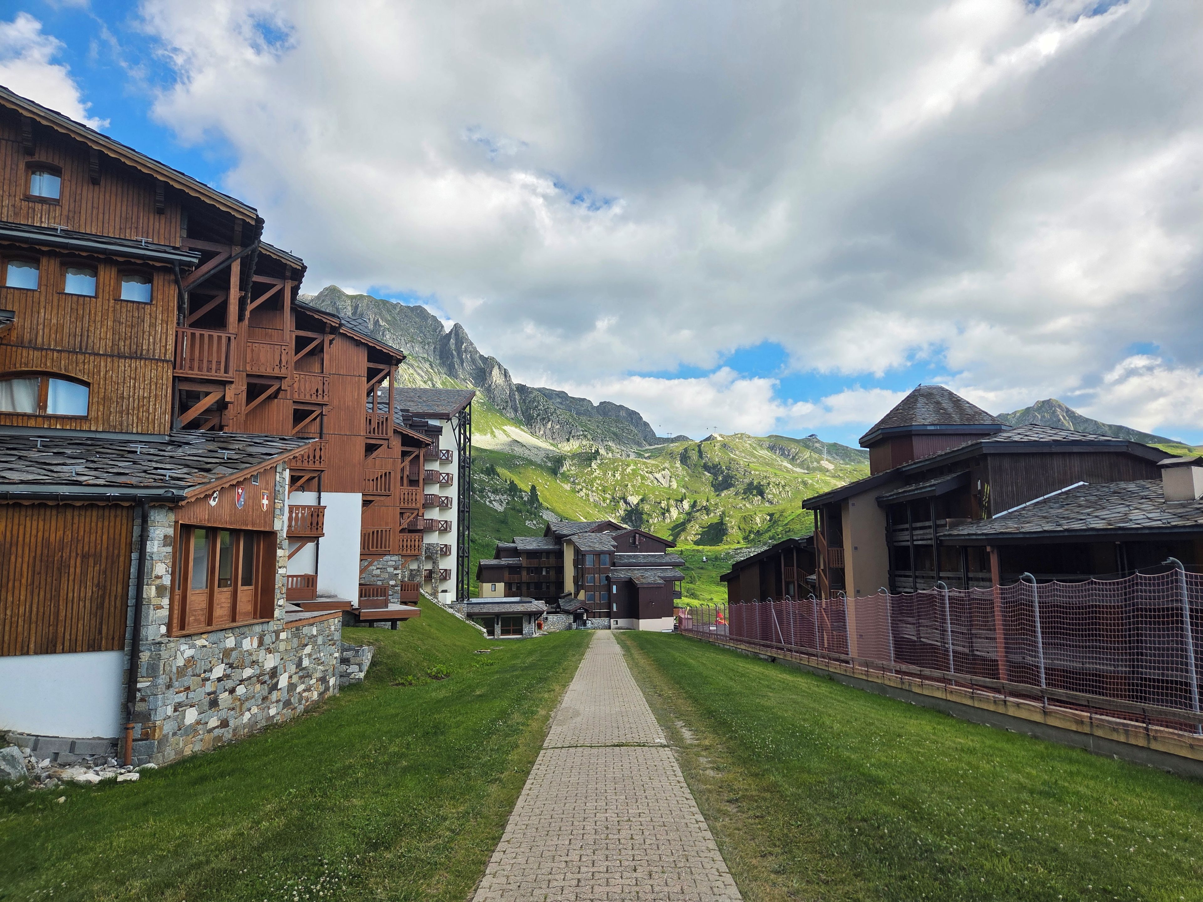 Un village de montagne aux maisons traditionnelles en bois, doté d’une promenade pavée et offrant une vue sur les montagnes.