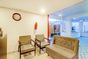 A waiting area with a clock, chairs, and a sofa. - Hotel O SS Skyline (Hyderabad)
