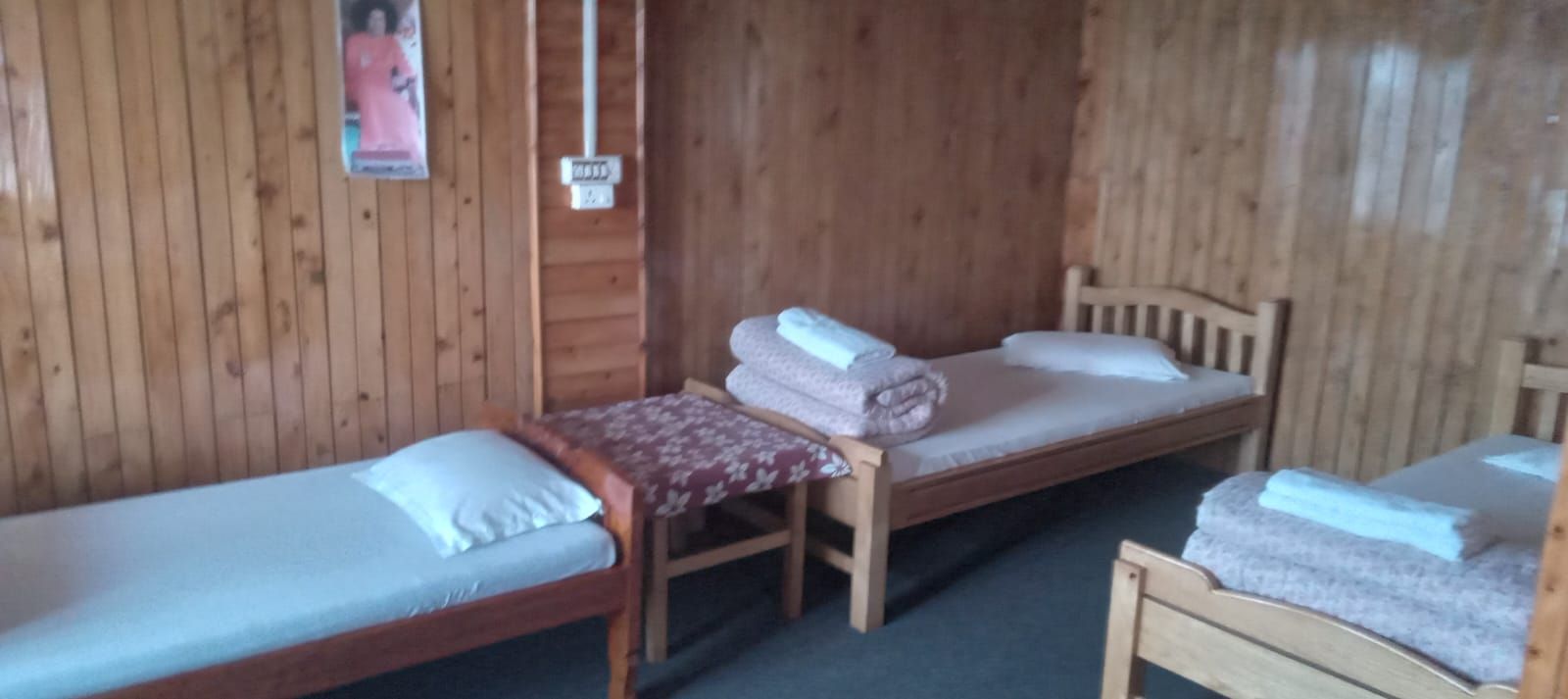 Une chambre avec deux lits en bois, chacun étant muni d’un oreiller et d’une serviette pliée.