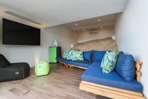 A modern living room with a flat-screen TV, a green ottoman, a blue sofa with patterned cushions, and a wooden coffee table. - Villa Moana Relaxed Tropical Retreat Samui (Koh Samui, Surhat Thani)