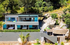 A modern two-story house with a balcony, a dining area, and a bedroom with a large bed. - Villa Moana Relaxed Tropical Retreat Samui (Koh Samui, Surhat Thani)