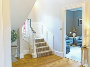 A staircase with a patterned carpet leading to a room with blue upholstered chairs and a vase with flowers. - 8 bedroom accommodation in Aboyne (Aboyne)