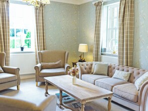 A room with a sofa, armchair, and a wooden table with books. - 8 bedroom accommodation in Aboyne (Aboyne)