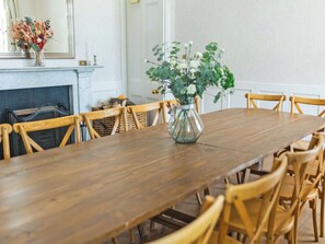 A dining room with a wooden table surrounded by chairs, a vase with flowers, and a fireplace. - 8 bedroom accommodation in Aboyne (Aboyne)