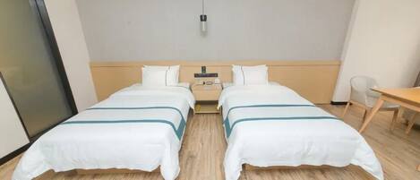 A hotel room with two single beds, a wooden headboard, a desk, and a chair.