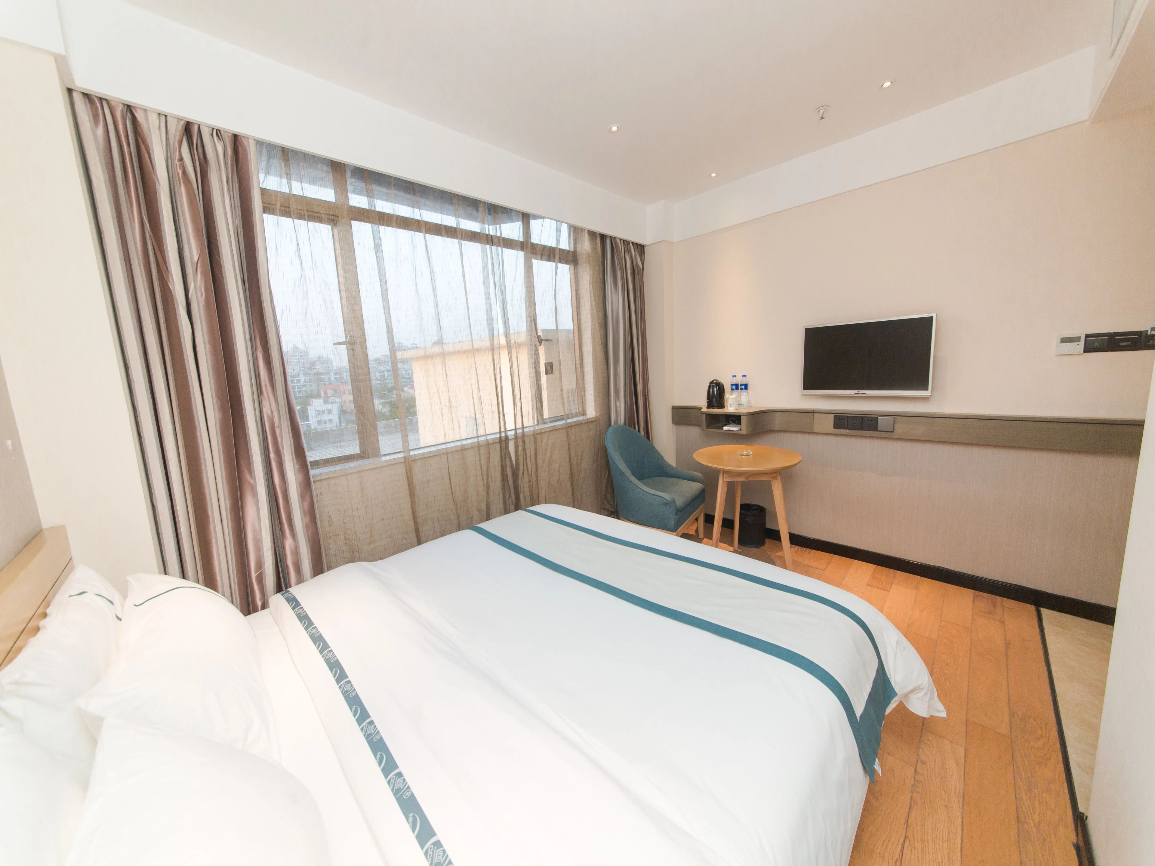 A hotel room with a bed, a TV, a small table, and a chair.