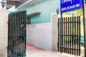 A gated entrance to a hotel with a blue sign above the gate.
