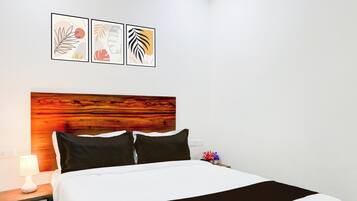 Una habitación de hotel con cama, mesita de noche, lámpara y tres cuadros en la pared.