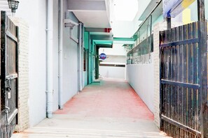 Un estrecho pasillo con alfombra roja, paredes blancas y un letrero azul que indica la recepción de un hotel.