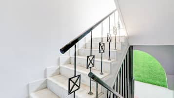 A staircase with white marble steps and black metal railings.