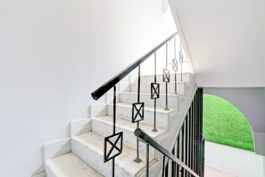 Una escalera con escalones de mármol blanco y barandillas de metal negro.